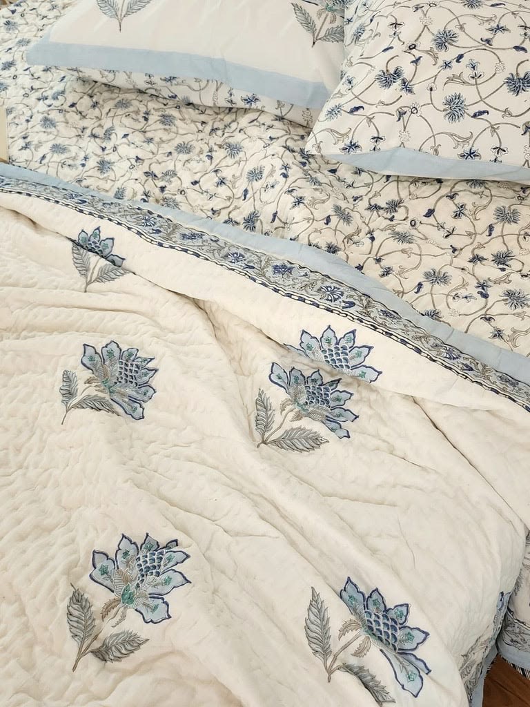 Cream bedding with blue botanical flowers, softly quilted texture and pale blue borders